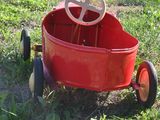 a red wagon with a steering sitting in the grass