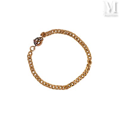 Le bracelet en chaîne d'or est orné d'une breloque en forme de cœur.
