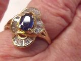 la main d'une femme tenant une bague sertie d'un saphir et de diamants