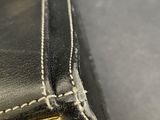 a close up of a piece of black leather with a gold clasp