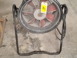 a fan that is sitting on a stand in a garage