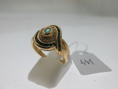 Gros plan sur une bague en or ornée d'une pierre verte
