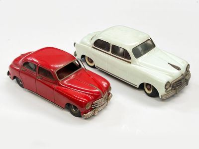 deux voitures jouets assises l'une à côté de l'autre sur une surface blanche