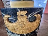 a gold bell on a black marble block on a table