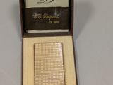 un briquet plaqué or dans un coffret en bois posé sur une table