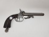 un vieux revolver avec une poignée en bois sur une surface blanche