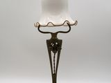 une lampe à l'ancienne surmontée d'un abat-jour en verre blanc