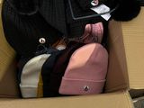 une boîte remplie de chapeaux et un sac sur lequel est accrochée une étiquette de prix