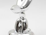 a silver sculpture of a bird sitting on top of a metal object