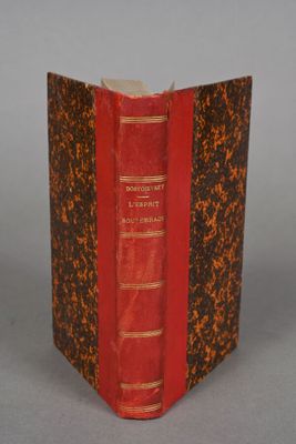 an old book with a red cover sitting on top of a table