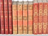 several old books are lined up in a row on a shelf