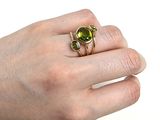 la main d'une femme tenant une bague sertie d'une pierre verte