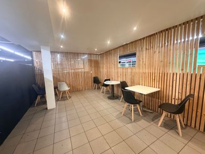 une pièce avec des tables et des chaises, et un mur composé de lattes de bois