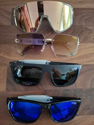 trois paires de lunettes de soleil à verres miroirs posées sur un support en bois