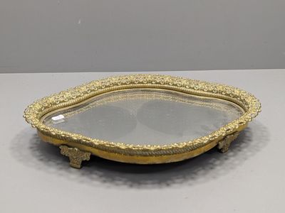 un plateau en or richement décoré, orné d'un miroir en son centre