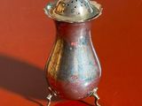 a silver vase with a lid on a red surface