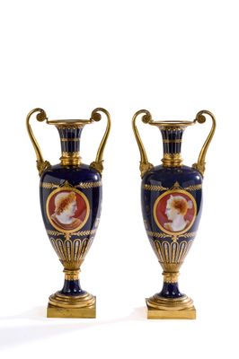 une paire de vases bleus et dorés posés sur une surface blanche