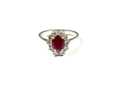 a close up of a ring with a ruby stone surrounded by diamonds