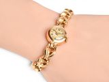 an image of a woman ' s wrist with a gold watch on it