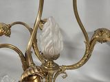 a gold chandelier with a glass candle holder on it