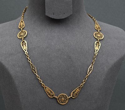 a gold necklace with a medallion design on a mannequin