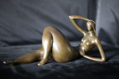 une statue en bronze représentant une femme allongée sur un canapé