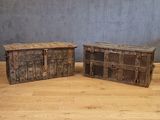paire de malles anciennes en bois avec des poignées métalliques, posées sur le sol en bois