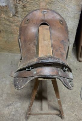 une vieille chaise en bois avec une assise en cuir, posée sur un socle