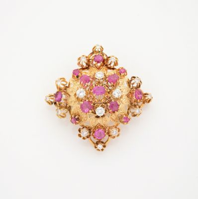 un gros plan d'une broche en diamants roses et blancs posée sur une surface blanche