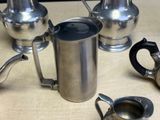 four silver teapots and two silver teapots on a table
