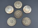 six silver coins are arranged in a circle on a black surface