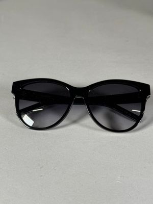 des lunettes de soleil noires de style « œil de chat » posées sur une surface blanche