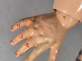 a close up of a doll ' s hand with red nails