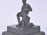 a small statue of a man sitting on a pedestal