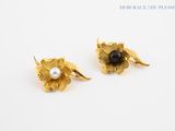 pair of gold and pearl flower earrings on a white surface