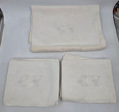 trois serviettes blanches ornées de monogrammes, posées sur une table