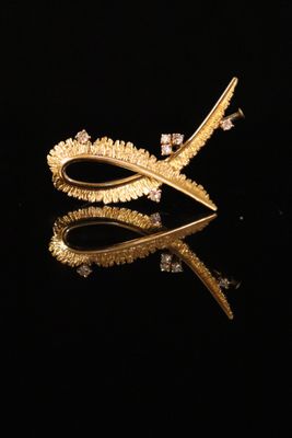 a close up of a pair of gold earrings on a black surface