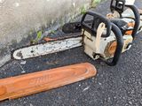 a chainsaw that is sitting on the ground next to a piece of wood