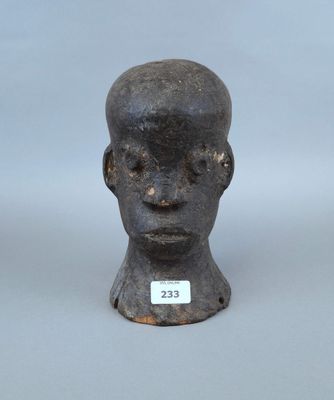 une image représentant la tête d'un homme sculptée, sur laquelle est accrochée une étiquette