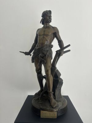 bronze statue of a man with a gun on a wooden base
