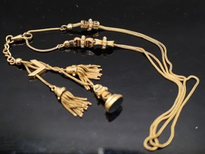 un gros plan d'un collier en or orné de pompons sur un fond noir