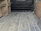 the inside of a van with a black door and a wooden floor