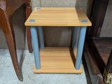 une petite table en bois aux pieds bleus, à côté d'une chaise