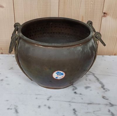 une grande casserole en métal posée sur une table en marbre