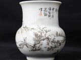 a white vase with a painting on it next to an orange vase