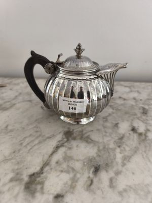 une théière en argent posée sur une table en marbre, avec une étiquette dessus