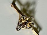 a gold brooch with a flower on it on a white surface