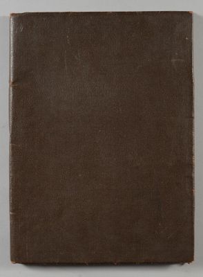 un vieux livre à la couverture marron posé sur une table blanche