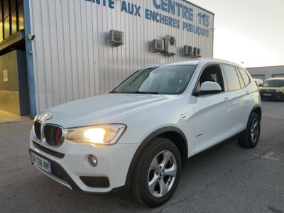 Le SUV BMW blanc est garé devant un immeuble.