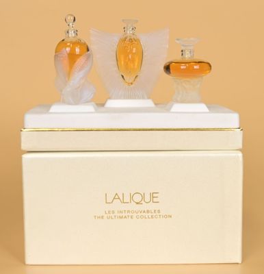 three bottles of perfume sitting on top of a white box